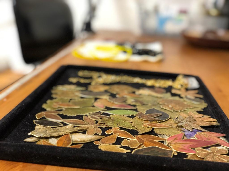 מגש עם עלים זהובים, יצירות אמנות על רקע שולחן עץ חום.