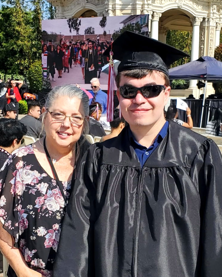 DSP Lorinda standing with Andrew in his cap and gown at his graduation