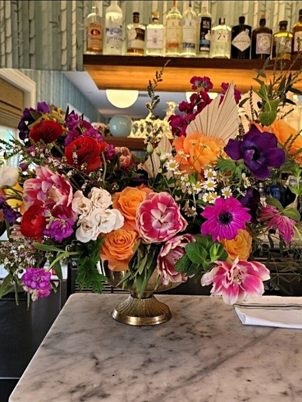 Colorful floral arrangement, bar setting with various liquors, Kitsch Floral And Ev.