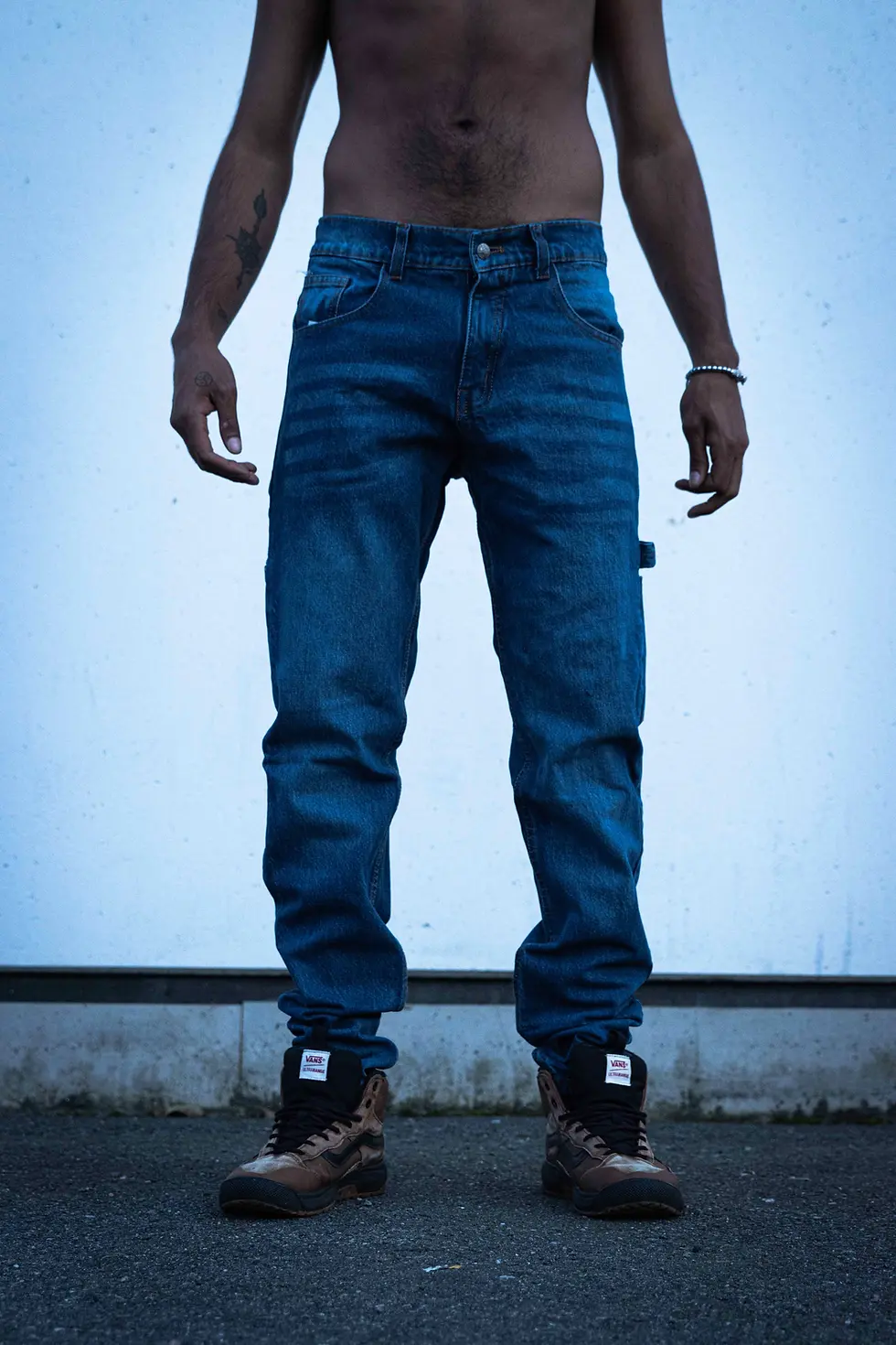 Front view of a person in blue jeans and brown shoes, standing on pavement.