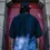 Thumbnail: Back view of a man in a black and Black gradient tee, standing in front of a red door with a stone arch
