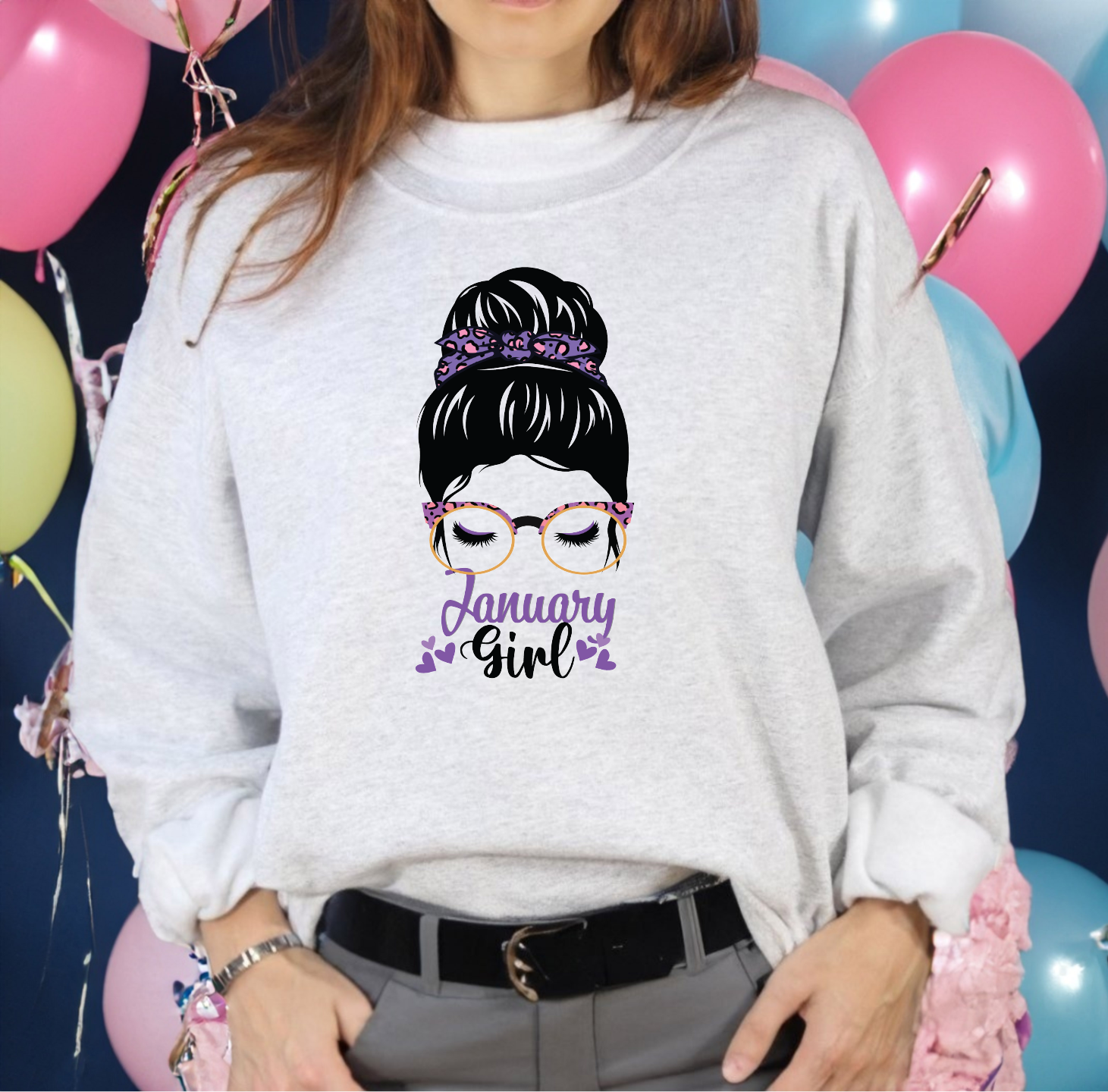 Woman graphic with a messy bun, gold patterned glasses, and tiny sparkles above text reading January Girl.