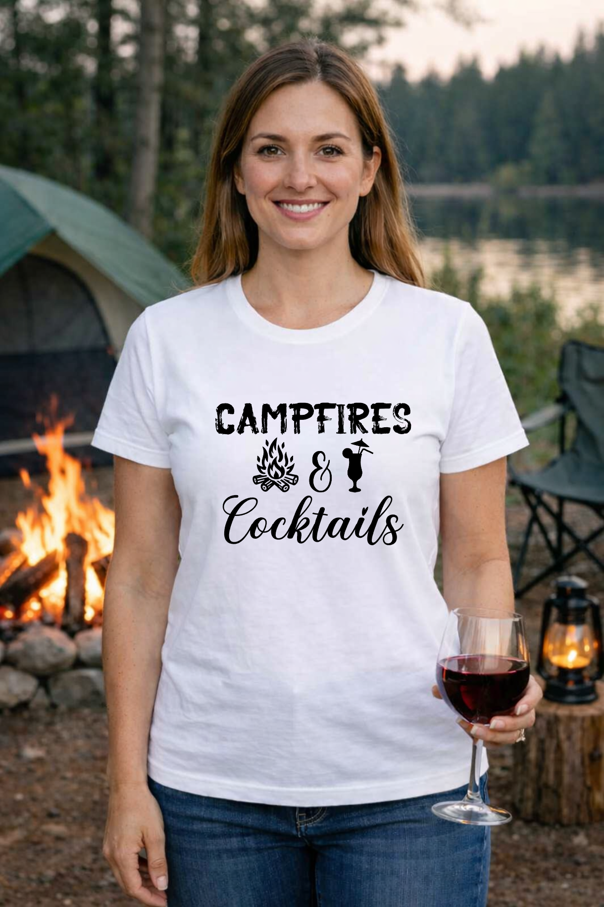 Smiling woman holding a wine glass next to a lake campfire, wearing a t-shirt that says Campfires and Cocktails.