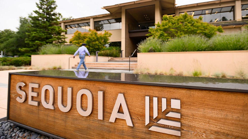 Man in blue walking up stairs in front of modern building with trees. Prominent "SEQUOIA" sign on a wooden block in the foreground.