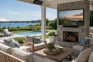 Outdoor TV installation on a covered patio in Southampton NY with poolside seating and water views