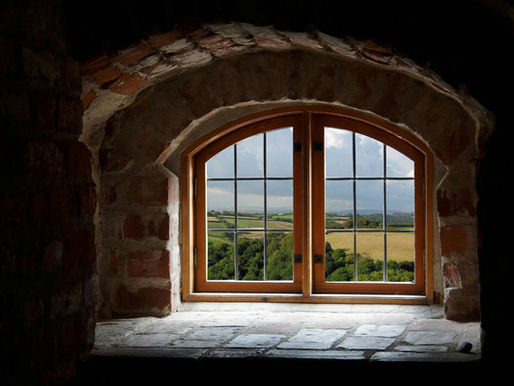 Looking out from a historic window across a rural landscape, illustrating anticipatory threat mitigation and intelligence-led risk management for private estates.