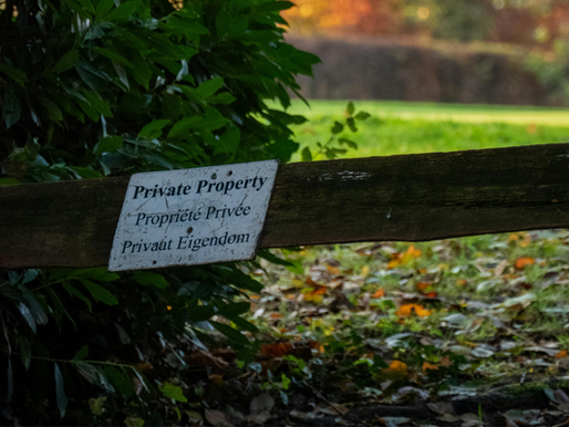 A weathered Private Property boundary sign on a rural estate, illustrating landowner duty of care and legal liability in risk management.
