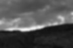 Moody liminal spaces landscape with dark clouds over hills.