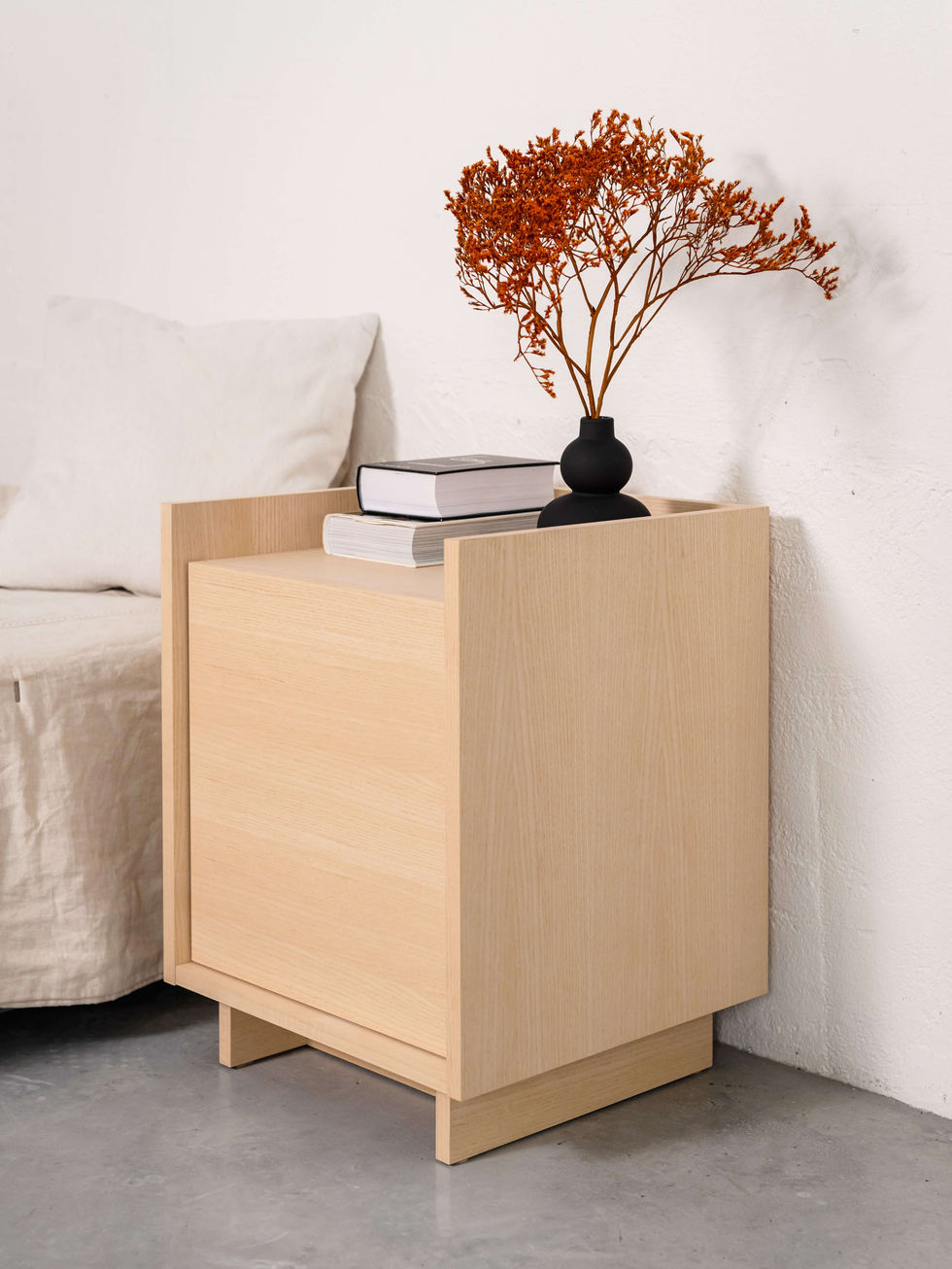 Wooden nightstand with books and dried flowers in a vase