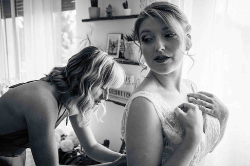 Photo de la future mariée qui se fait aider avec sa robe de mariage