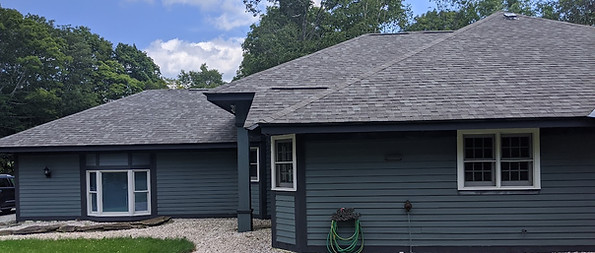 A house featuring a gray roof and a paved driveway leading up to the entrance.