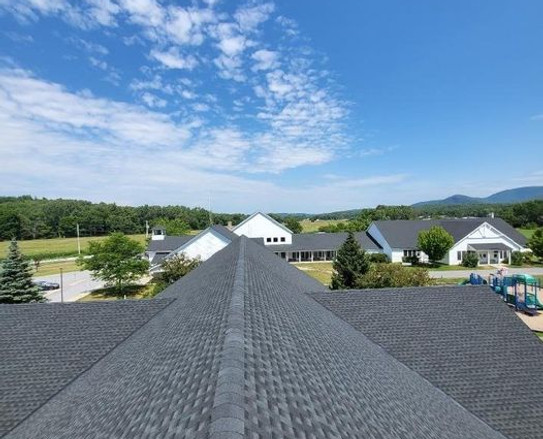A house roof under a clear blue sky, showcasing a bright and sunny day.