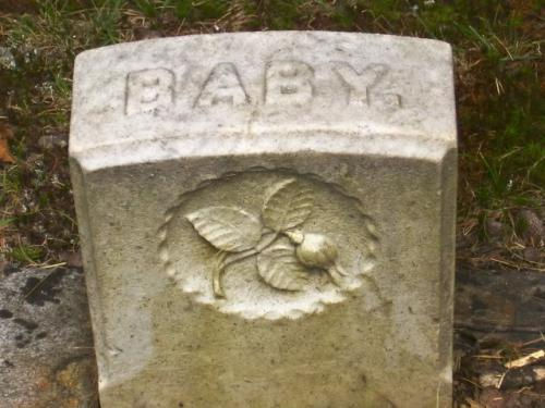 Gravestone carving of a rose with a broken bud symbolizing the death of a young woman.