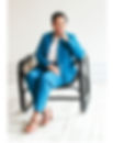 Photo of Kristy Farewell sitting on a chair in a blue suitq