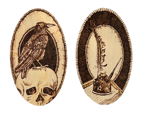 Two wooden oval plaques side by side on white background. The left one shows a pyrography drawing of a raven perched on top of a human skull. The right plaque shows a quill sticking out of an inkwell.