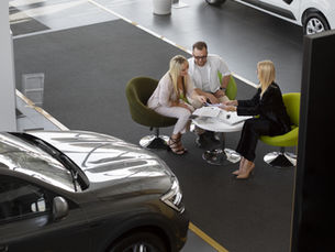 Casal falando com vendedora de carros em loja de carros
