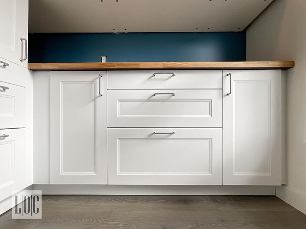 white cabinet with wood countertop and blue wall