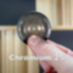 a single chromium jingle held between a finger and thumb