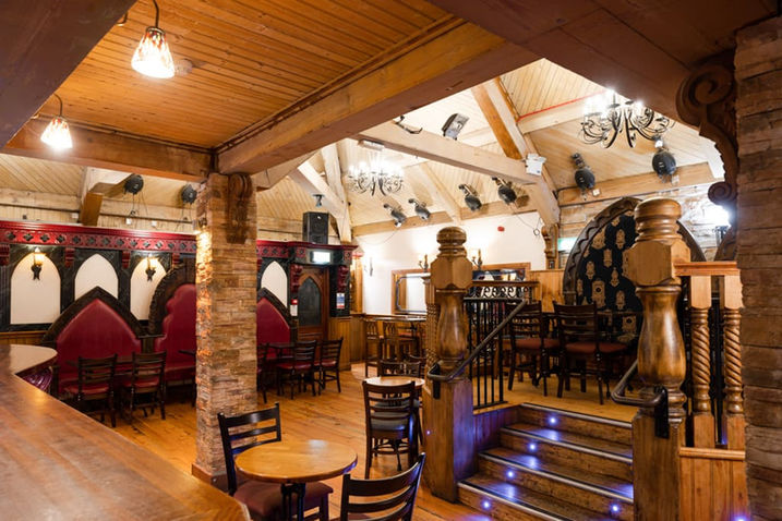 Traditional seating area in Charlie's Bar Upstairs Lounge with wooden beams, red booth seating and authentic Irish pub décor.