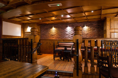 Seating area below three downward spot lights on the stage area of the main bar.