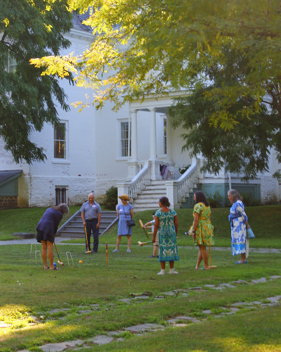 Croquet players in front of mansion