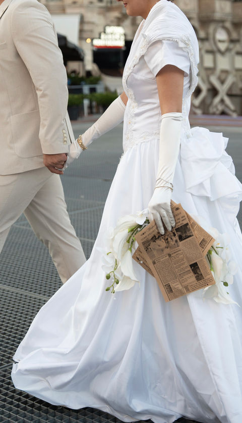El ele tutuşan gelin ve damat, gelin beyaz elbiseli, çiçekli.