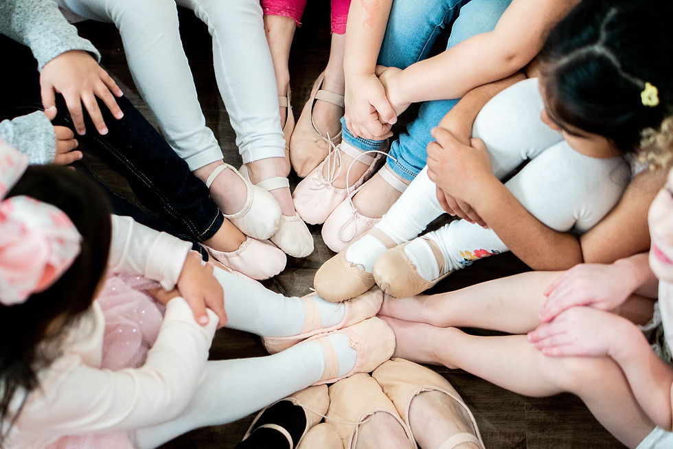 Children dancers putting their toes together in the middle. Ballerina shoes on, and huddled up together.