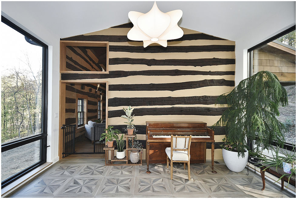 Modern breezeway with geometric gray floor tile, large black-framed windows, piano, plants, and cabin-inspired feature wall by tj bush enterprises