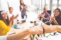 Photo of people sitting at a table with two fists 