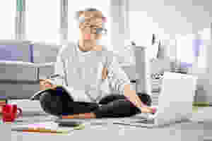 lady with legs crossed sitting on the living room floor with laptop and note pad