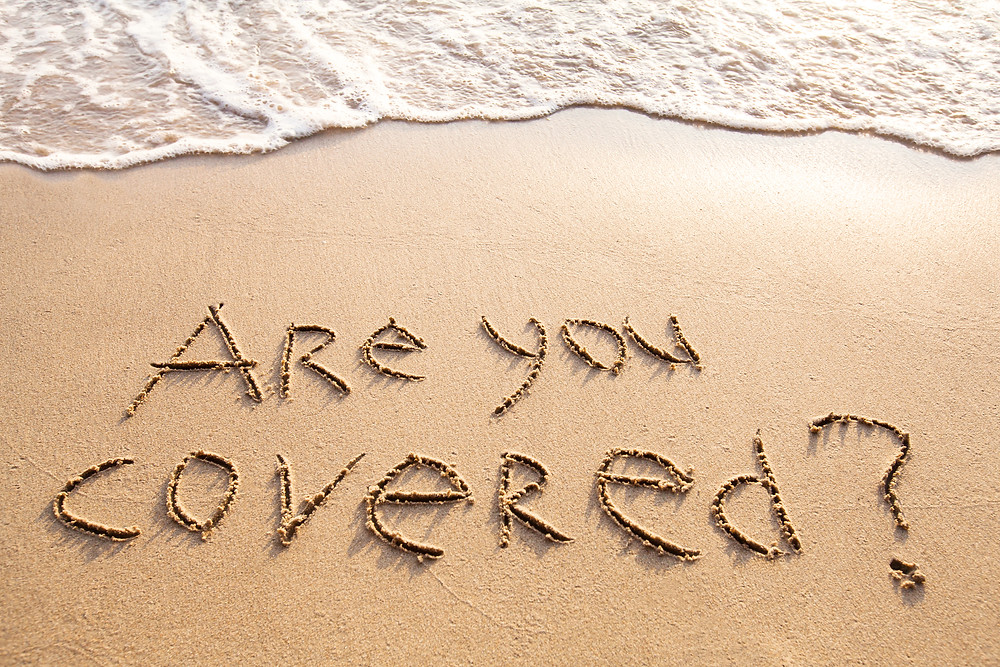 sandy beach with text are you covered drawn in sand