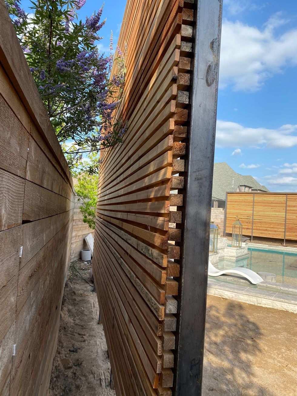 A close-up view of a modern wooden slat privacy wall with a narrow gap next to another wooden wall, beside a backyard pool and clear blue sky in the background—perfect for stylish outdoor privacy without needing mobile welding.