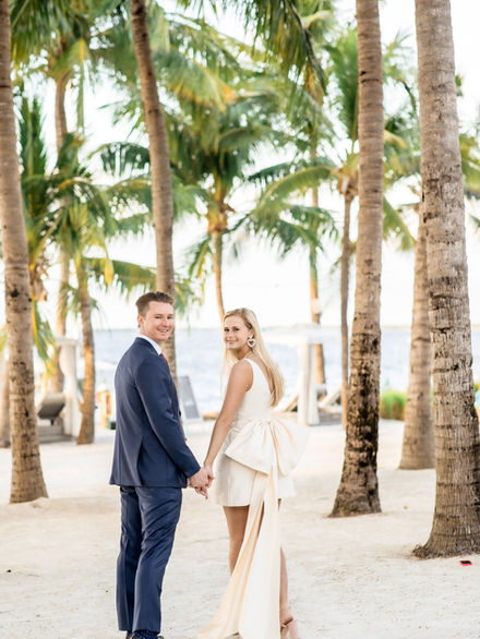 Bride and groom walking on the beach in the Florida Keys. Under the palm trees. 