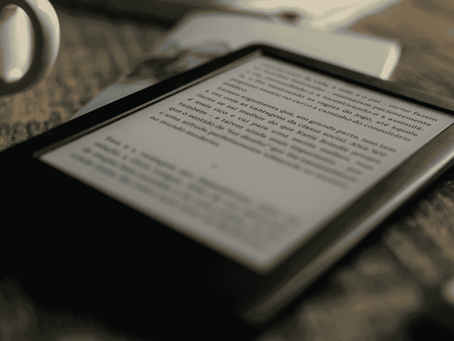 kindle sobre a mesa ao lado de uma xÃcara de café