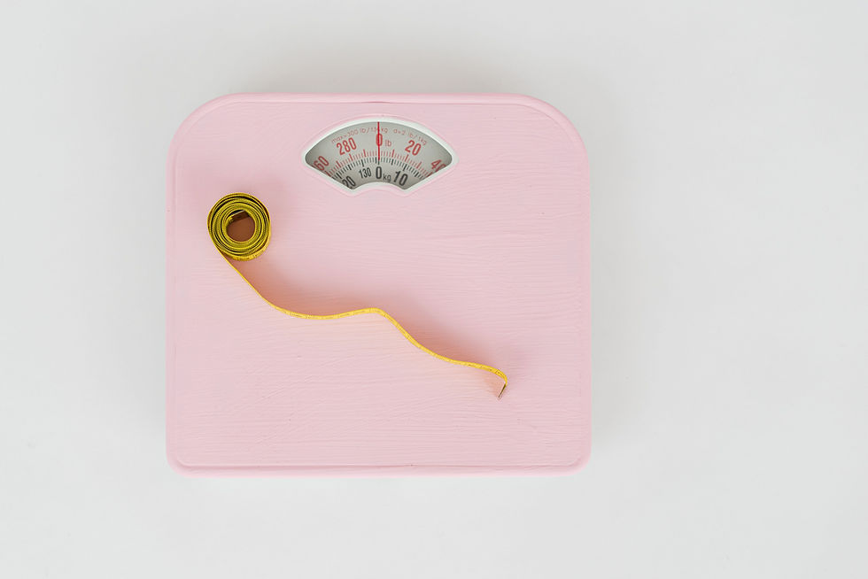 Pink bathroom scale with a yellow measuring tape coiled on top, needle at zero, on a white background with lb/kg markings.