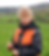 Woman in a field inspecting green plants.