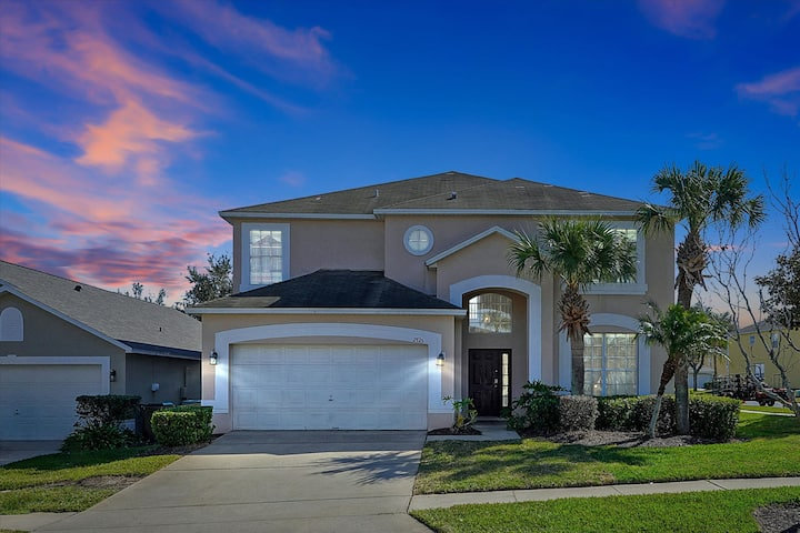 Two-story villa with palms under a pink and blue dusk sky