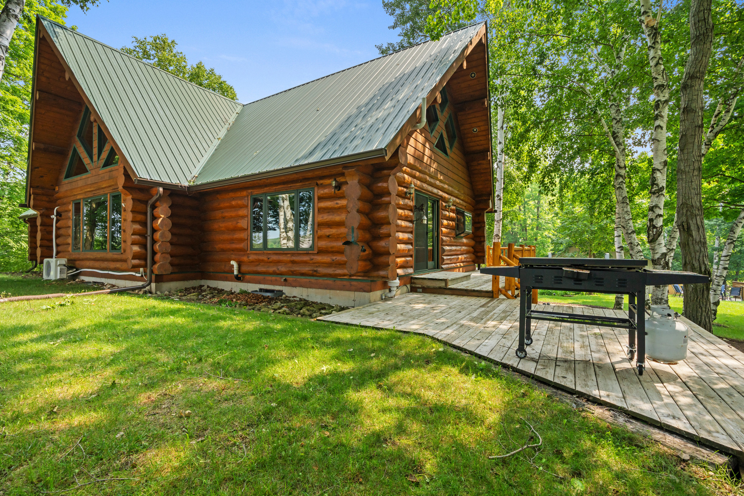 Side of the log cabin with a timber gable and a grill on the deck