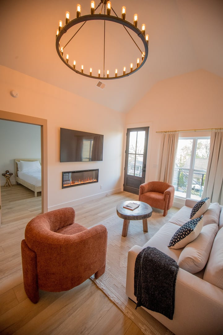 Living room with a linear fireplace, rust armchairs and tall windows