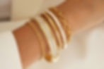 Elegant stack of gold and white enamel Florence London bracelets photographed for jewellery brand SEO and product marketing.