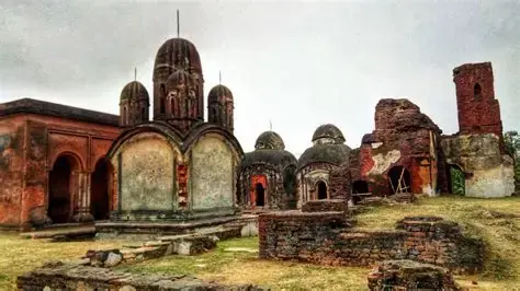 Ancient brick temple ruins with domed structures in an overcast setting. Weathered red and gray tones dominate the aged architecture.