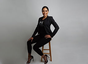 Nicole dressed in all black sitting on a wooden chair
