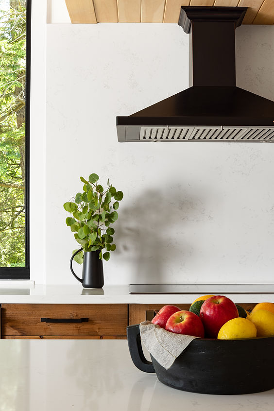 Muskoka cottage kitchen with fruit bowl on quartz countertop island, wood cabinetry, black range hood, black hardware