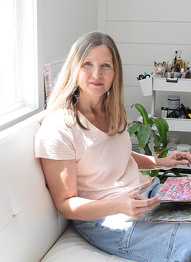 Melissa Rolfes sitting in her studio looking through one of her art journals.