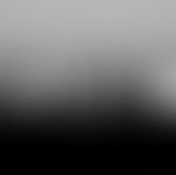 Black and white photo of city skyline at dusk, with illuminated skyscrapers and mountains in the background, creating a serene mood.