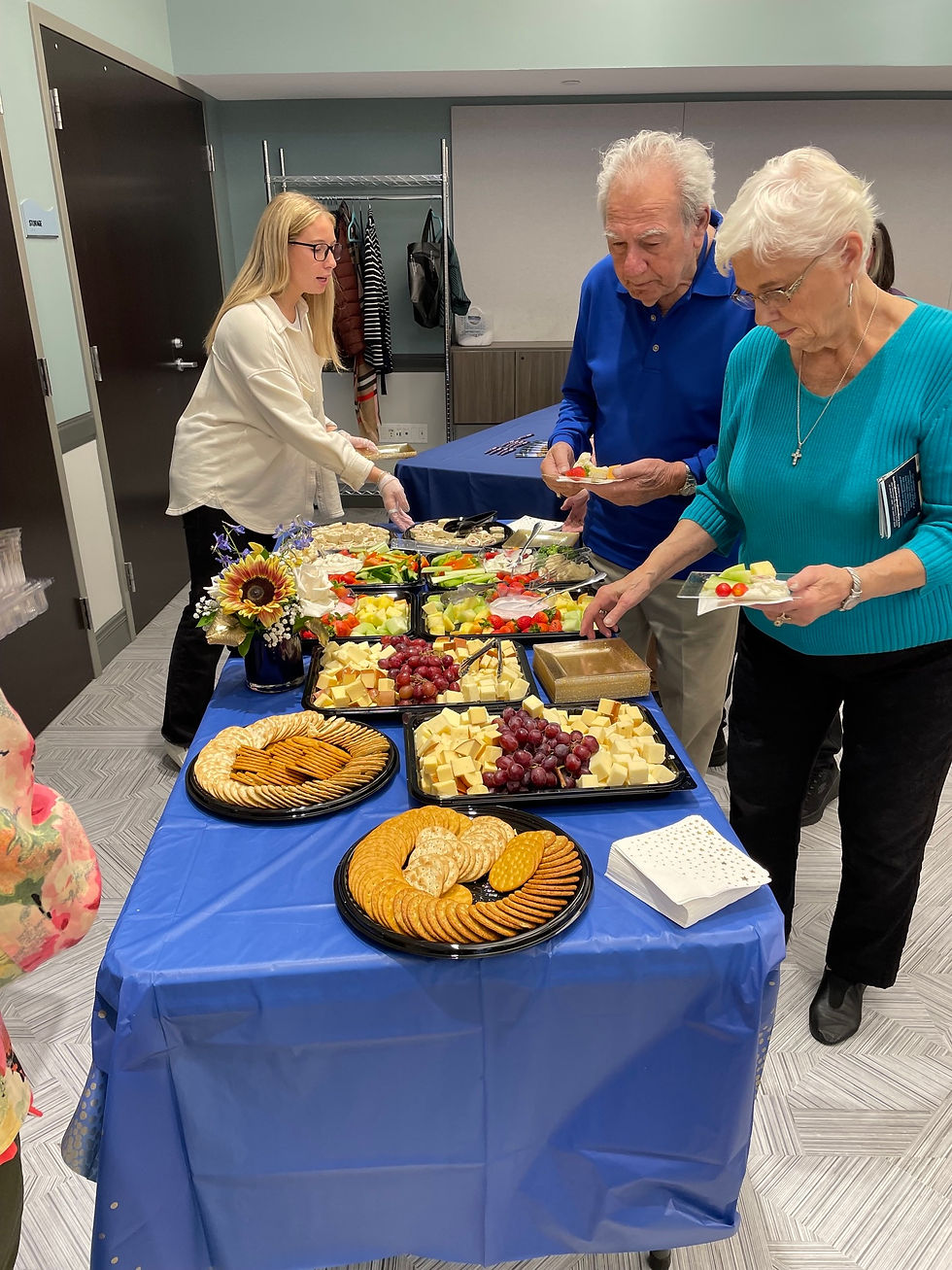 Guests select treats from a table offering various types of appetizers.