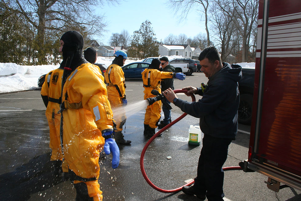 Capt. Pedro Machado washes down the volunteers who donned protective suits to train for cold-water rescues. Many bodies of water in town contain contaminants and Mill Park Pond, for example, is contaminated by runoff that includes fecal matter from Canada geese that feed on the park’s grass.