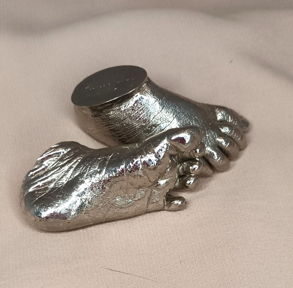Nickel-plated baby feet castings on soft fabric background, durable silvery finish for long‑lasting keepsakes.