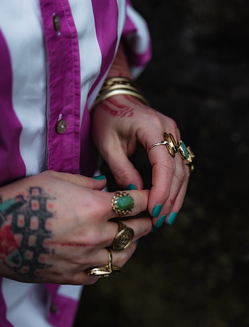 Vrouwelijke handen met gouden ringen en tatoeages en groene nagels