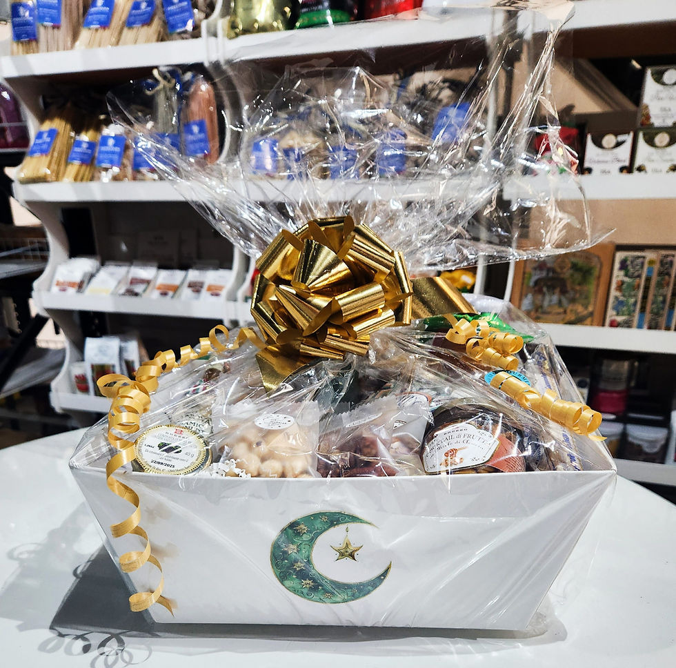 Gift basket wrapped in clear plastic with a gold bow, containing assorted foods. A crescent moon design is on the basket. Shop shelves in background.